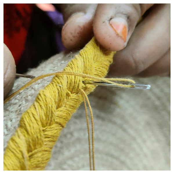 Crocheting fíos amarelos brillantes con gancho metálico a man, mostrando artesanía intrincada.