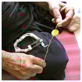 Elaboración de obxectos amarelos con fío, tesoiras, aneis. Vestimenta negra, tatuada.