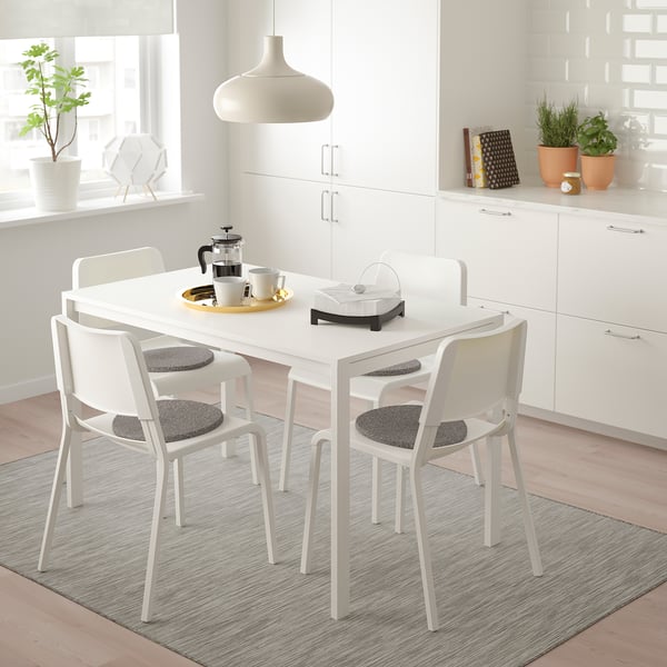 Comedor minimalista con mesa MELLTORP, cadeiras, cafeteira e tazas.