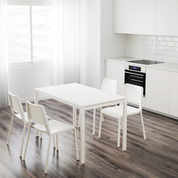 Mesa de comedor branca MELLTORP e tres cadeiras apilables nunha cociña compacta.