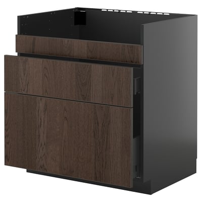 Unha unidade de cociña ikea METOD de marrón escuro ensamblada con fachadas de madeira e lados negros, incluíndo caixóns e un armario.