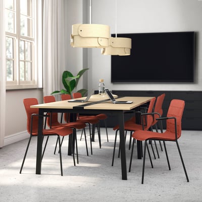 Mesa de conferencias con cadeiras vermellas, televisión, cortinas na sala moderna.