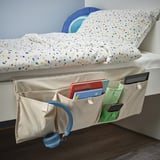 O peto de almacenamento da cama contén libros, tableta, teléfono, auriculares; colgado no bordo da cama.