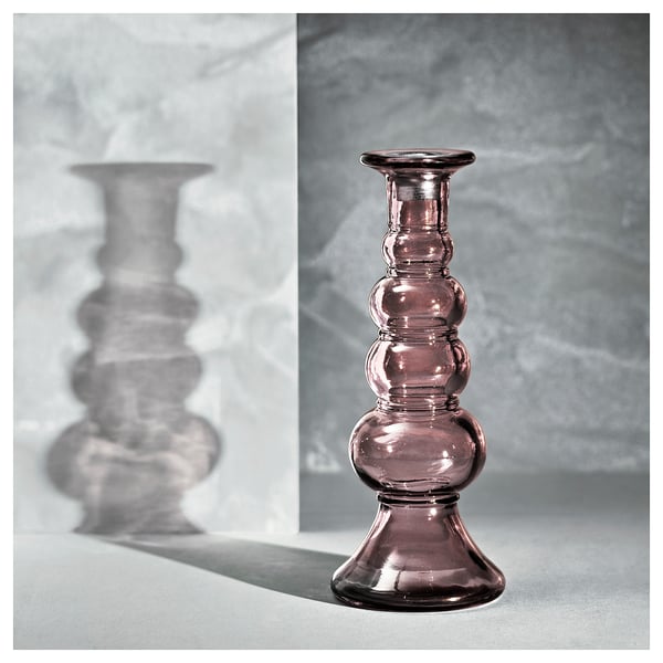 Mostra un soporte de candelabro de vidro púrpura con base de aluminio, colocado sobre un fondo de mármore gris.