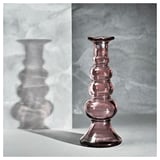 Mostra un soporte de candelabro de vidro púrpura con base de aluminio, colocado sobre un fondo de mármore gris.