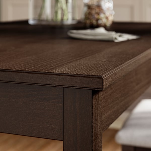 Mesa de comedor de madeira escura con superficie pulida, bordos cadrados, gran visible, acabado robusto e elementos decorativos.