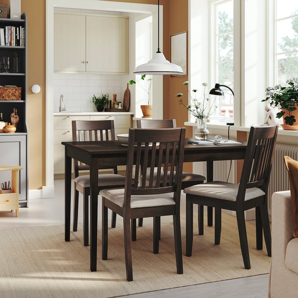 Comedor acolledor con mesa escura e cadeiras grises, luz natural, encanto de granxa.