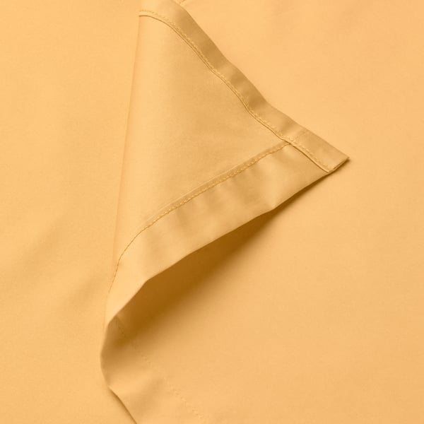 Primeiro plano de saba de cama suave, amarelo dourado que amosa tecido fino e costura limpa.