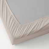 Folla beige sobre superficie branca, bordos elásticos, tecido de algodón natural.