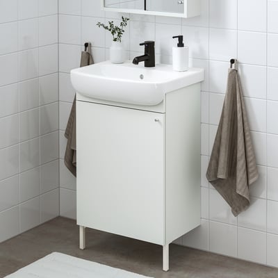Configuración de baño branco moderno: pequena lavabo vanidade, billa negra, toallas grises. Aforra espazo cun deseño elegante.