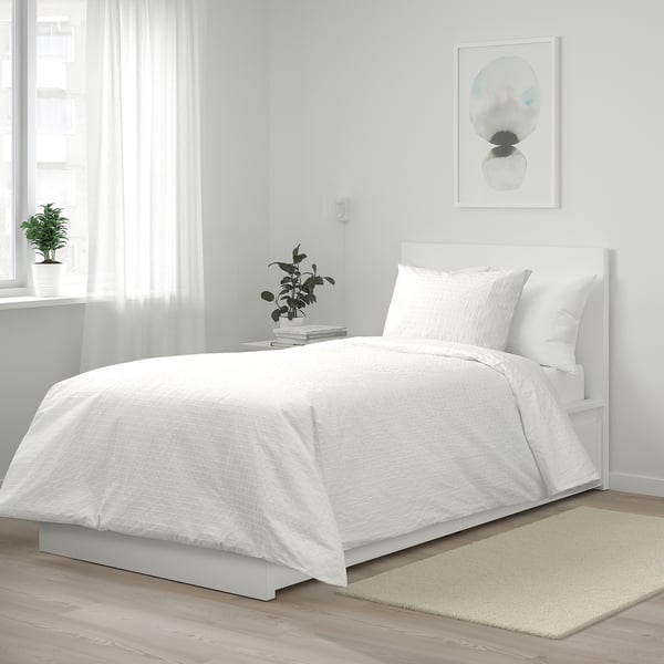 Conxunto de duvets brancos OFELIA VASS: algodón nítido, texturizado, deseño minimalista, encaixa perfectamente baixo a arte da parede, con pequenas plantas ao lado.