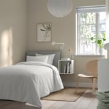 Dormitorio neutro con cuberta de pido OFELIA VASS. Cama branca, cabeza gris, cadeira de madeira. Estilo minimalista e de luz.