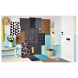 Entrada luminosa con alfombras de cores, flip flops colgantes de portas, ganchos de parede, banco con flores e unha porta con cesta e reloxo.
