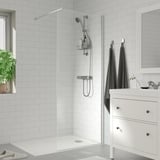 Baño moderno con ducha OPPEJEN branca, toallas grises, armario branco e planta.