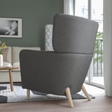 Cadeira gris moderna con pernas de madeira nunha habitación acolledora, proporcionando confort con respaldo alto e brazos.