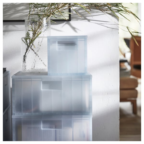 Caixas PANSARTAX transparentes apiladas con vaso de plantas en interiores.