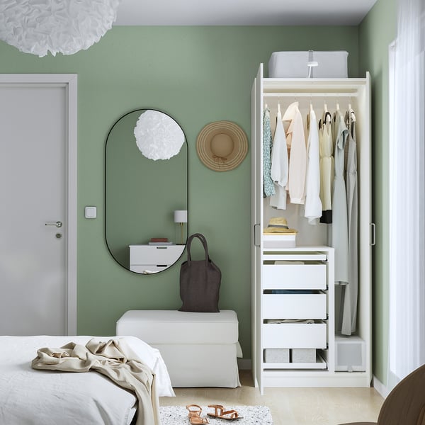 Dormitorio moderno con parede verde, armario branco PAX, almacenando a roupa ordenadamente.