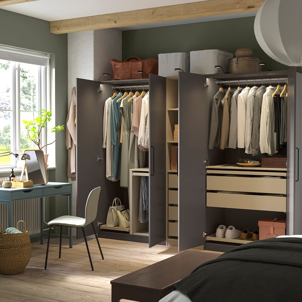 Dormitorio moderno que amosa un armario PAX con portas abertas, revelando roupa ben organizada, estantes e solucións de almacenamento.