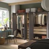 Dormitorio moderno que amosa un armario PAX con portas abertas, revelando roupa ben organizada, estantes e solucións de almacenamento.
