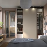 Dormitorio moderno con armarios PAX, cama e mesa de noite.