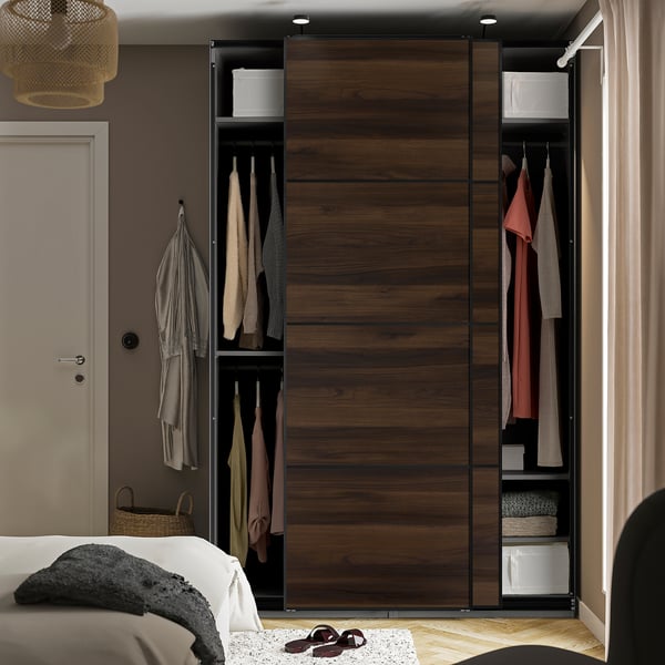 Armario de dormitorio con roupa e acabado de madeira escura, luces interiores.