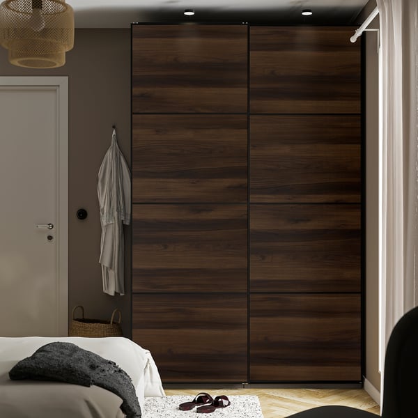 Dormitorio moderno con gran armario PAX de madeira. As portas deslizantes aforran espazo, altas e anchas, cama correspondente e pequena luz colgante.