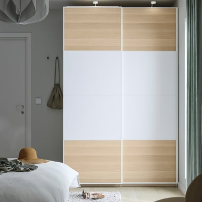 Dormitorio minimalista con armario PAX, madeira clara, portas deslizantes brancas. Cama, alfombra pequena, sombreiro beige, bolsa.