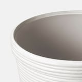 Presenta unha plantadora moderna con sucos horizontais. O exterior branco contrasta cun interior gris claro, mostrando o seu deseño elegante e elegante.