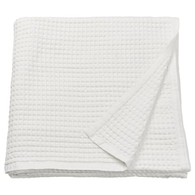 Unha cuberta de cama branca e dobrada de PELARTUJA feita de algodón 100% cunha textura de tecido de waffle. É reversible e axeitado para unha cama dobre.
