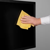 A man con pano amarelo limpa a superficie negra, asegurando un resultado brillante e sen raias.