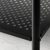 A imaxe mostra un primeiro plano dun estante de metal negro, destacando a súa robusta construción e deseño perforado para a ventilación.