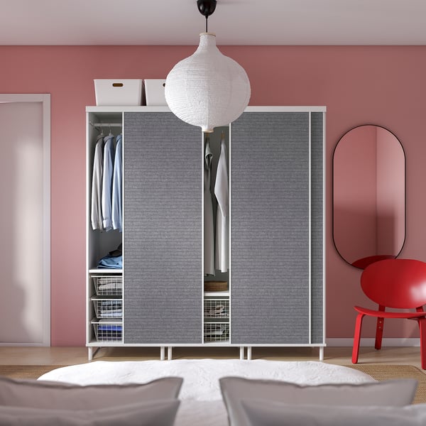 Dormitorio minimalista con armario PLATSA, cadeira vermella, luz colgante.