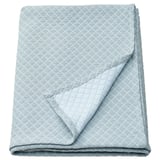 Cuberta de cama dobrada azul claro con patrón de diamantes.