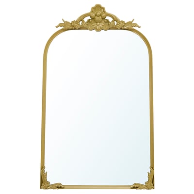 Un espello RÅMEBO de cor dourada e decorado con intrincados ornamentos de estilo vintage. Ten unha parte superior de arco e forma rectangular.
