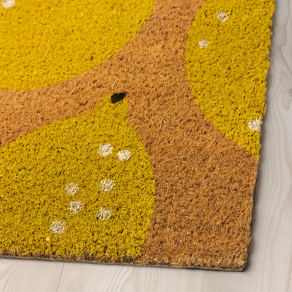 Alfombra amarela brillante con manchas brancas nun chan de madeira, material de coir de alta calidade.