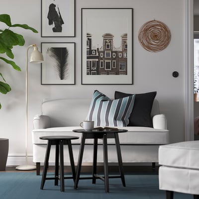 Sala de estar moderna cun sofá branco ROCKSJÖN, mesa de café negra, almofadas a raias e alfombra gris. A arte e as plantas decoran o espazo.