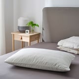 Almofada RUMSMALVA na cama con cabeceira gris, quilted, preto de lámpada e planta.