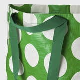 Bolsa verde con puntos brancos, con correas fortes e axustables para un transporte cómodo.