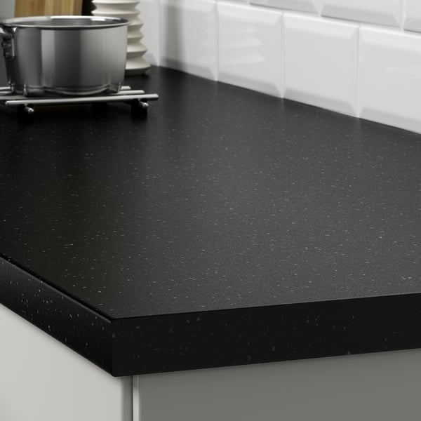 Mesa de cociña negra con manchas, resistente a derramamentos e graxas, mostrada con potas e utensilios.