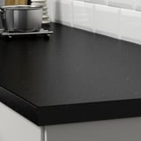 Mesa de cociña negra con manchas, resistente a derramamentos e graxas, mostrada con potas e utensilios.