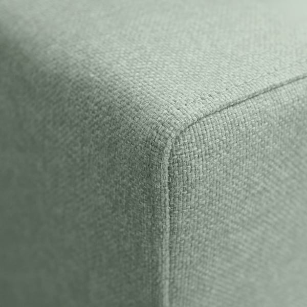 Primeiro plano dun recuncho de alta calidade dun sofá verde claro, mostrando o seu tecido texturizado e as costuras resistentes.