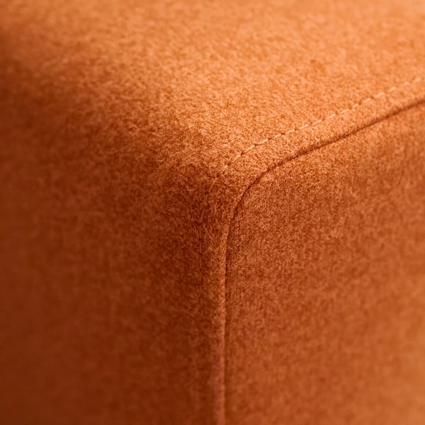 Primeiro plano da costura dun sofá marrón, mostrando costuras precisas e tecido suave, destacando a súa construción de calidade.