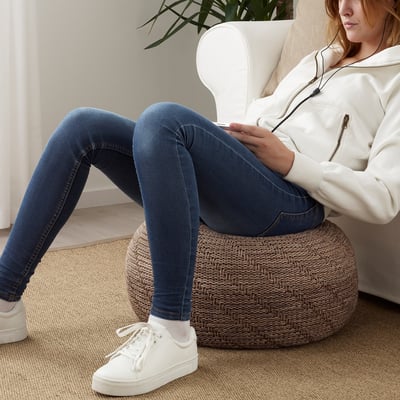 Persoa sentada nunha cadeira branca, usando o teléfono intelixente, planta de casa preto.