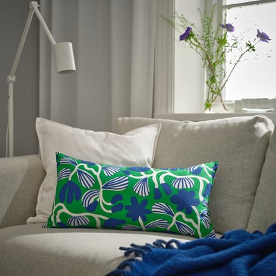 Almofada de algodón SANDMOTT verde / azul con deseño floral no sofá gris, preto da lámpada branca.