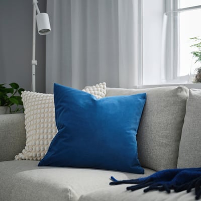 Coxín azul SANELA sobre sofá gris, máis grande que as almofadas decorativas, sala de estar moderna.
