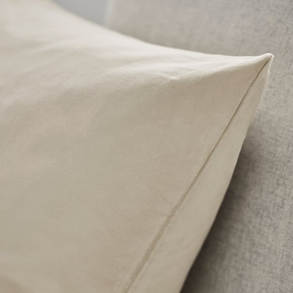 Primeiro plano de coxín beige nunha cadeira tapizada, mostrando veludo de algodón suave e texturizado.