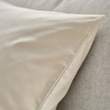 Primeiro plano de luxoso cuberta de coxín de veludo beige suave nunha cama, mostrando textura suave e acabado elegante.