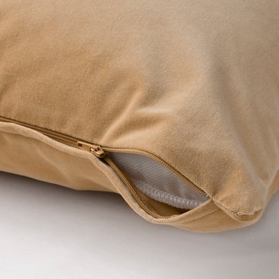 Unha cuberta de coxín de veludo beige cunha cremalleira, que amosa un tecido suave e texturizado axeitado para unha limpeza fácil.