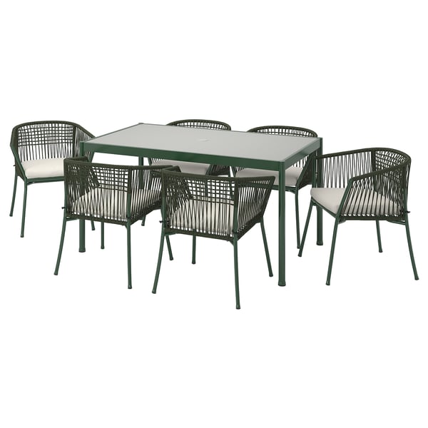 Conxunto de comedor ao aire libre moderno con mesa de vidro cadrado e catro cadeiras de vimbio verde con coxíns brancos.