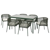 Conxunto de comedor ao aire libre moderno con mesa de vidro cadrado e catro cadeiras de vimbio verde con coxíns brancos.